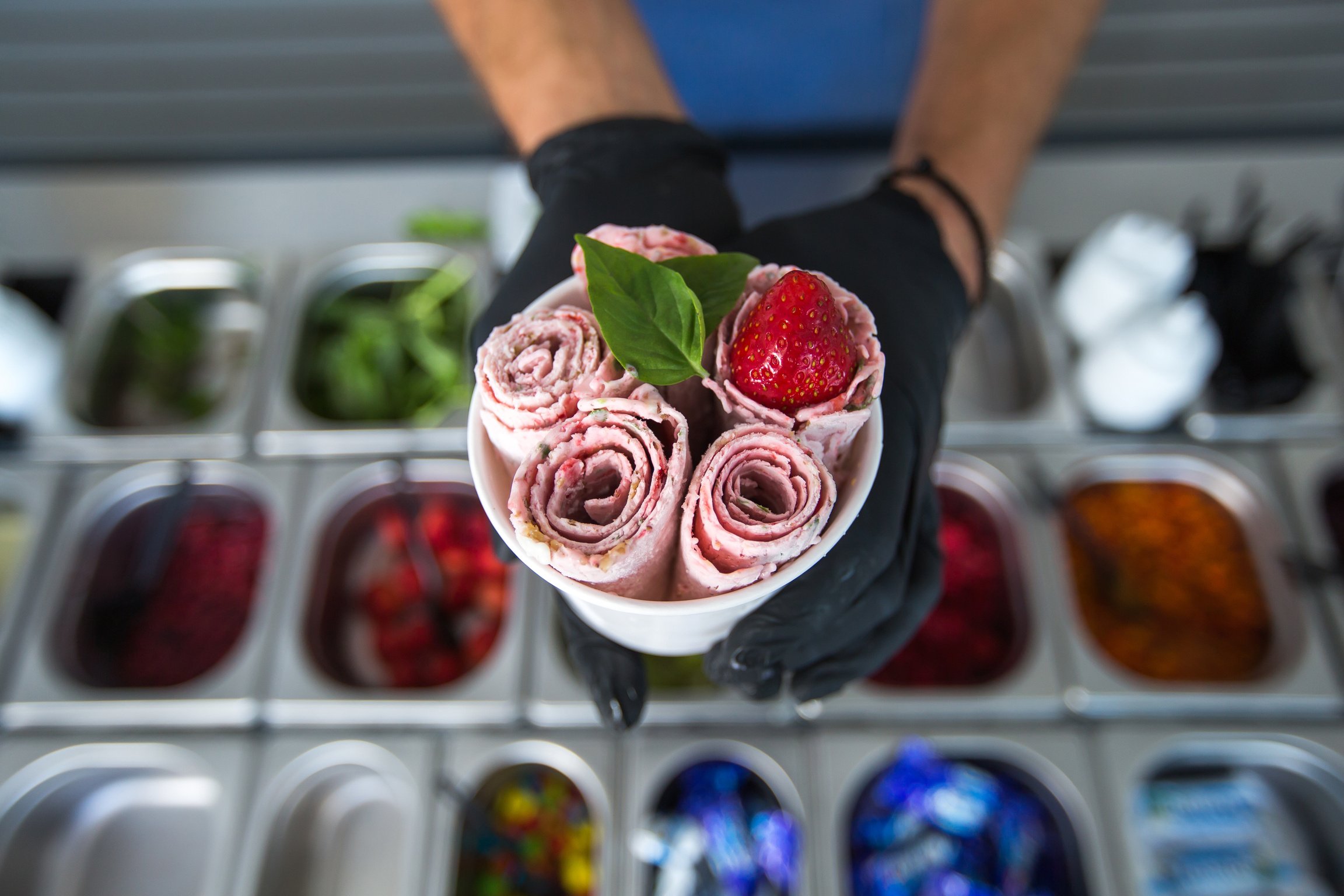 Stir-fried ice cream rolls at freeze pan. Rolled ice cream, hand made ice cream dessert. Fried ice cream machine with steel chilled pan.